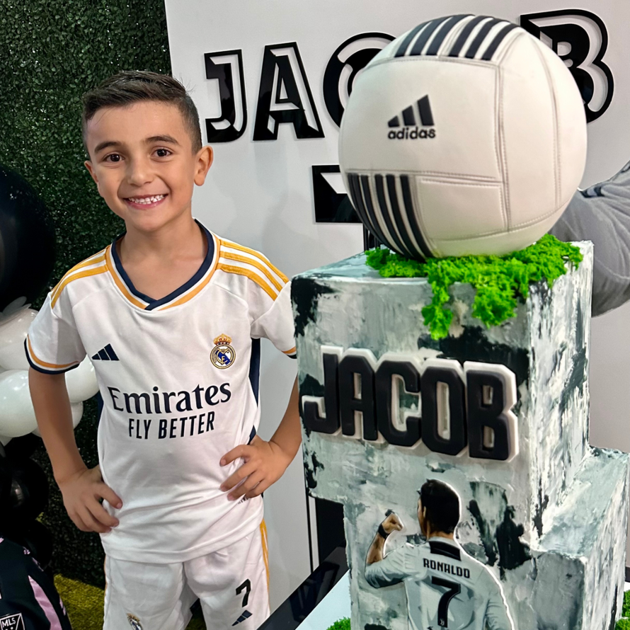 Birthday boy with soccer party supplies and cake