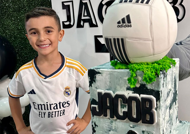 Birthday boy with soccer party supplies and cake